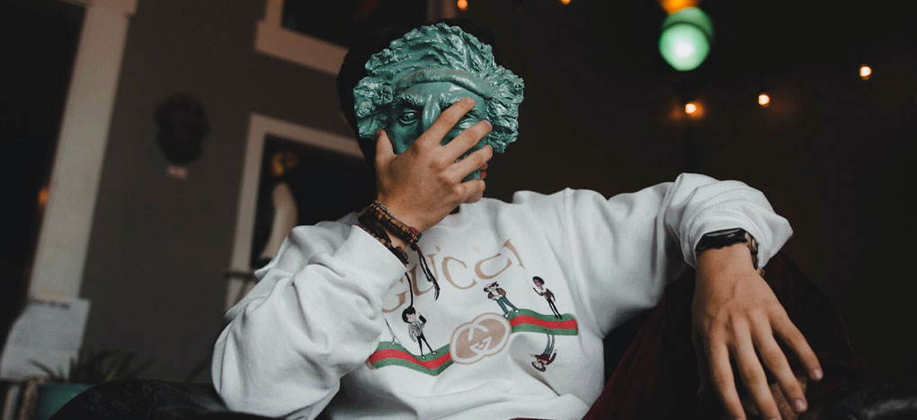 Man in Gucci clothes covering his face with a mask
