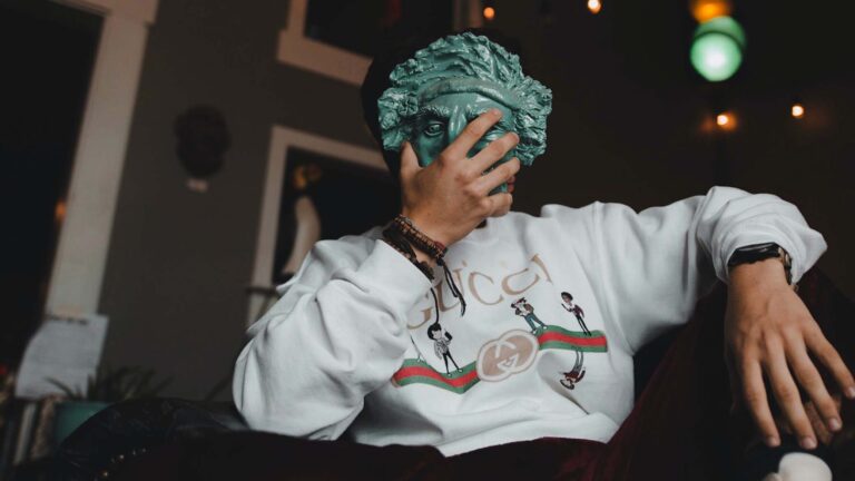 Man in Gucci clothes covering his face with a mask