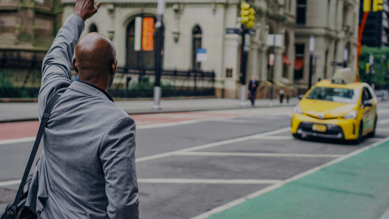 black man in suit hailing yellow taxi